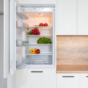 Close-up van een minimalistische keuken met witte kastjes en een inbouw koelkast waarvan de deur open staat